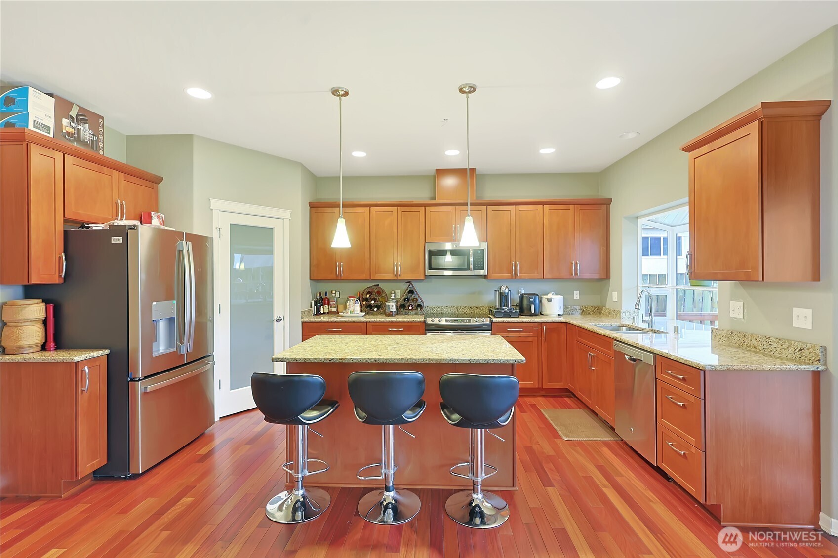 11107 Southeast 162nd Street, Unit B Renton, WA 98055 - Photo 8 of 15 a kitchen with stainless steel appliances granite countertop a refrigerator a stove top oven and a dining table with wooden floor