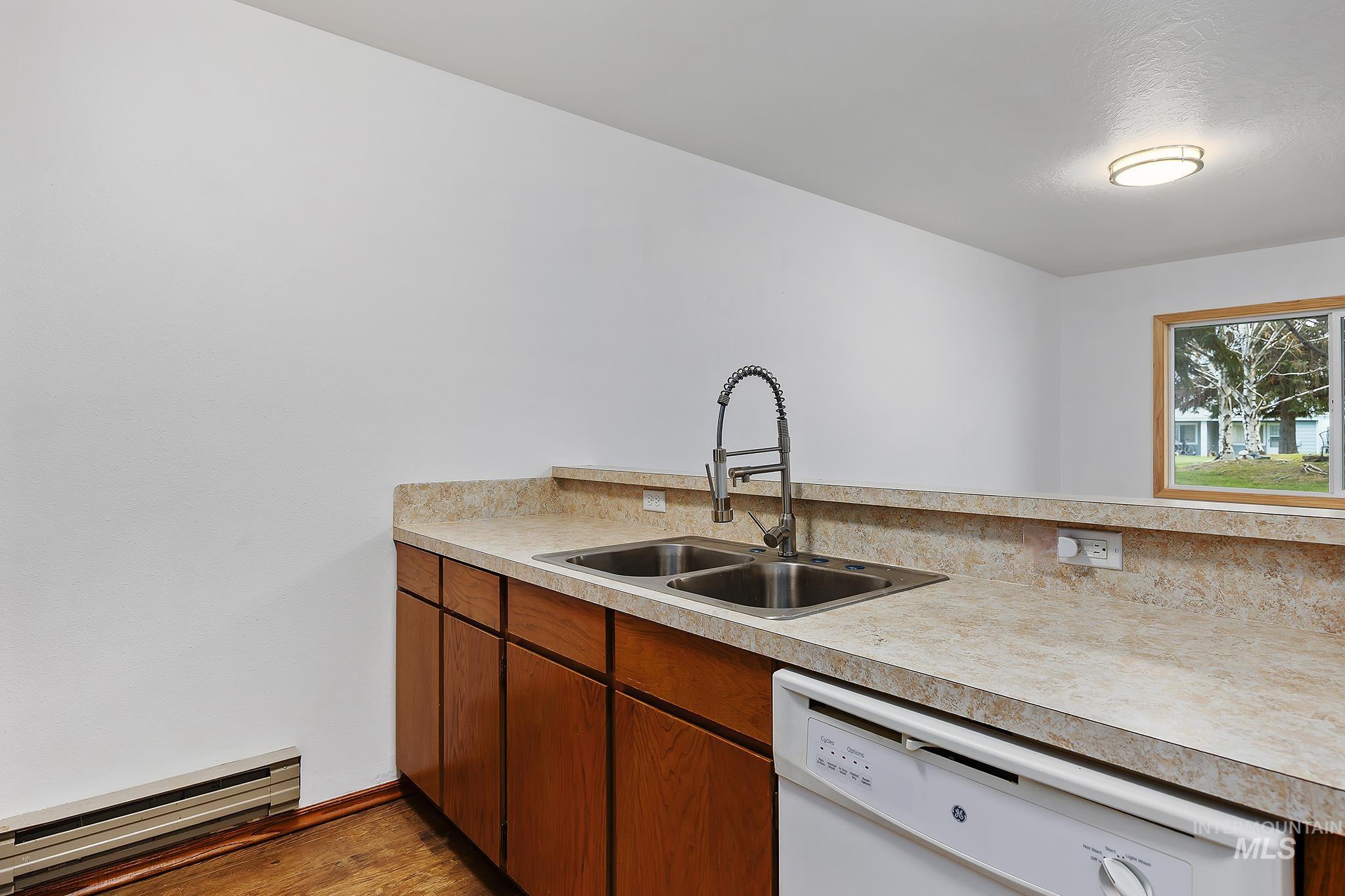 511 Union Avenue Filer, ID 83328 - Photo 13 of 25 Kitchen with brown cabinets, a baseboard radiator, white dishwasher, and light countertops