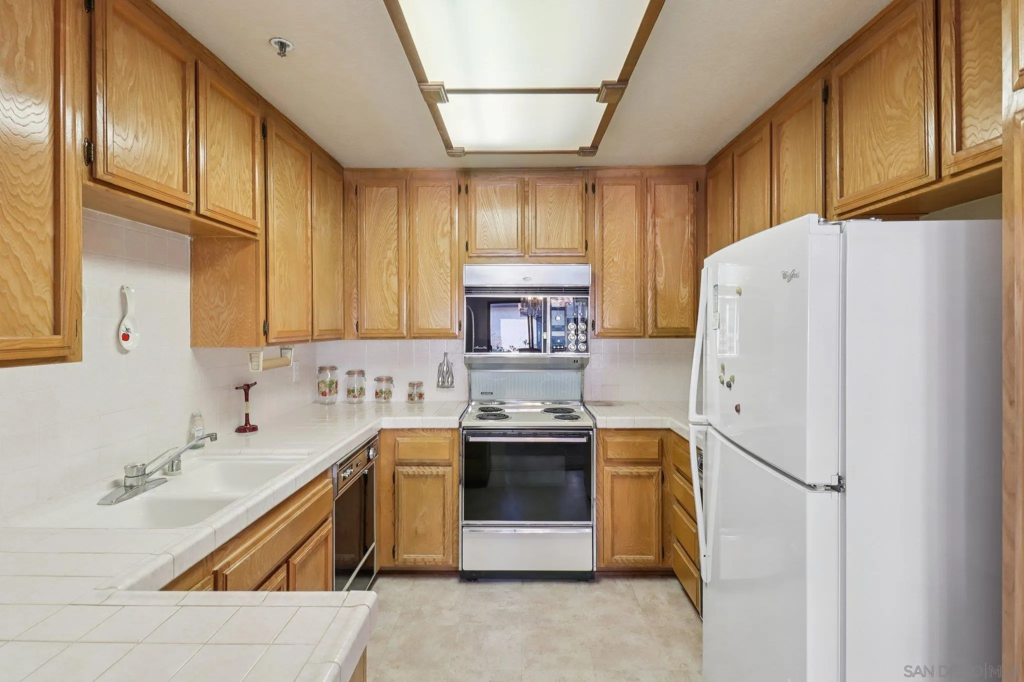 5645 Friars Road, Unit 386 San Diego, CA 92110 - Photo 25 of 72 a kitchen with stainless steel appliances granite countertop a refrigerator a sink dishwasher a stove with wooden cabinets