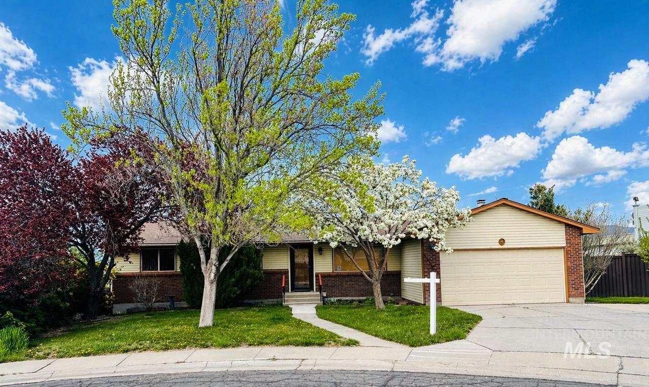 1204 West Sunrise Rim Road Boise, ID 83705 - Photo 1 of 1 Single-family residence featuring a brick and siding exterior, concrete driveway, attached garage, and mature trees including one with white blossoms