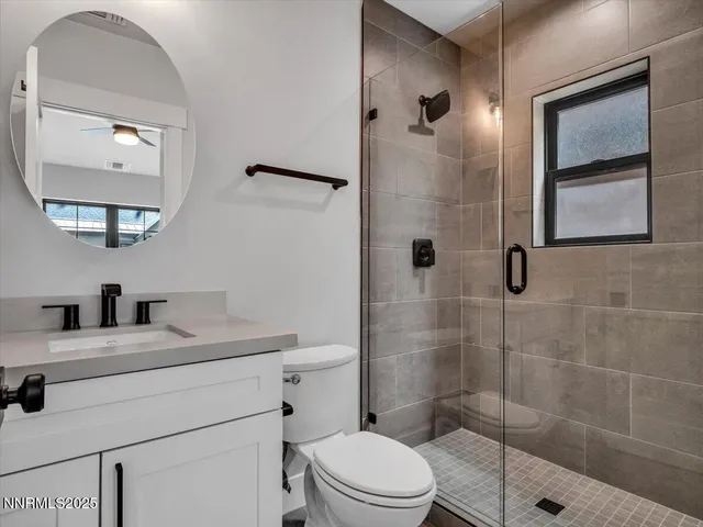 a bathroom with a granite countertop sink a mirror and shower