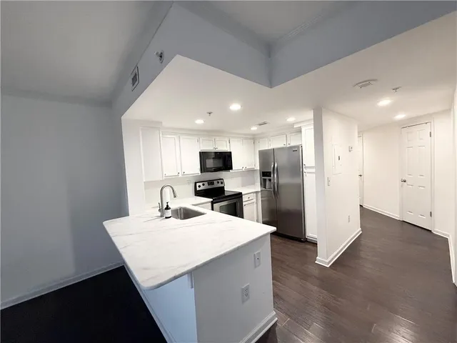 a kitchen with stainless steel appliances kitchen island granite countertop a refrigerator and a sink