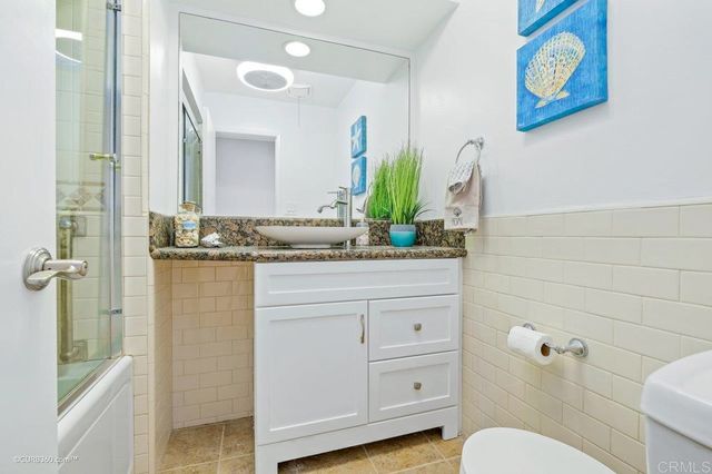 a bathroom with a granite countertop sink a toilet and a mirror