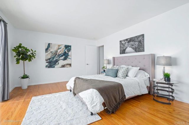 a bedroom with a bed painting on wall and a potted plant