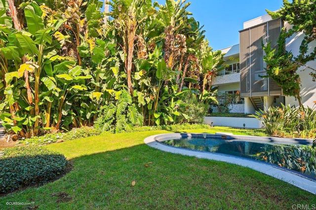a view of pool with lawn chairs and large trees