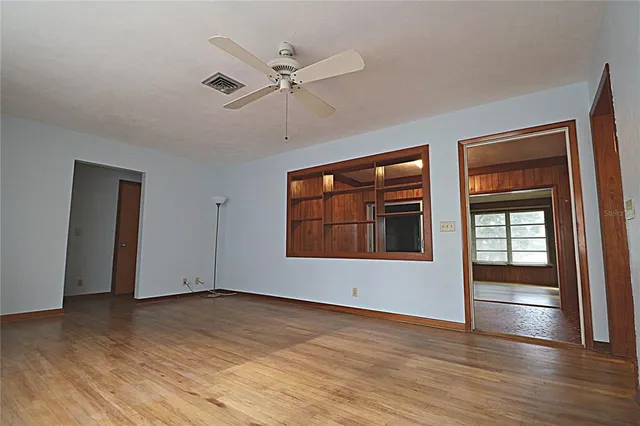 a view of empty room with wooden floor and fan