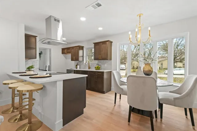 a kitchen with stainless steel appliances kitchen island granite countertop a table chairs and a refrigerator