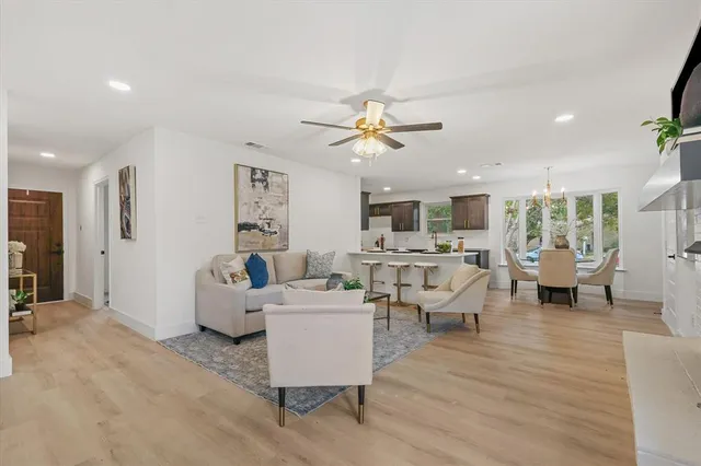 a living room with couches and kitchen view with wooden floor