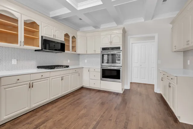 a kitchen with stainless steel appliances white cabinets a sink and a stove