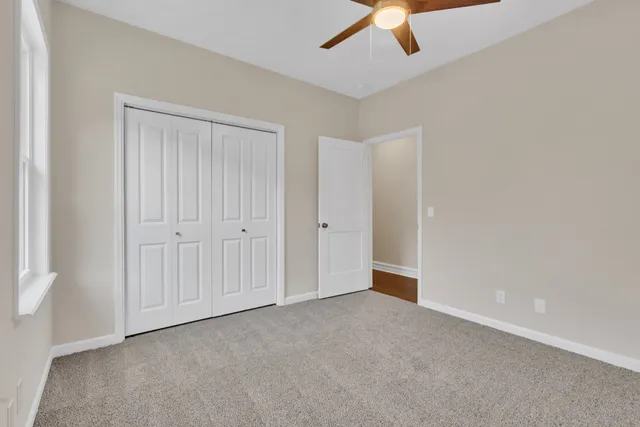 an empty room with a ceiling fan and carpet