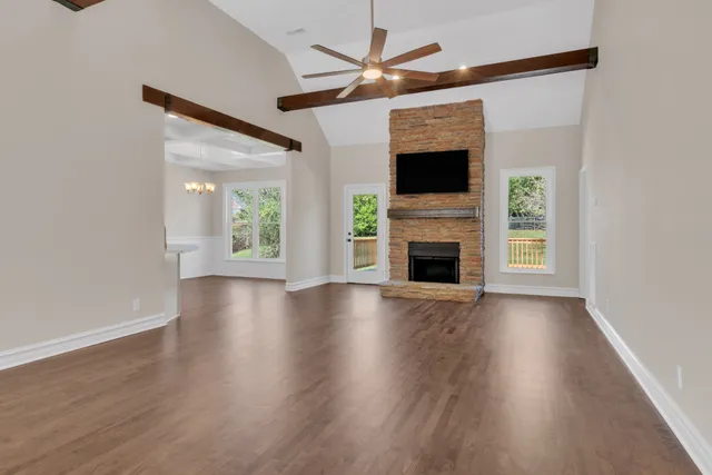 an empty room with windows fireplace and wooden floor