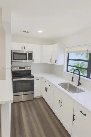 a kitchen with sink a microwave and cabinets