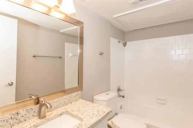 a bathroom with a granite countertop sink a toilet and shower