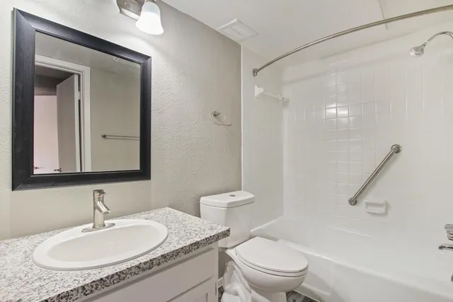a bathroom with a granite countertop sink a mirror and a toilet