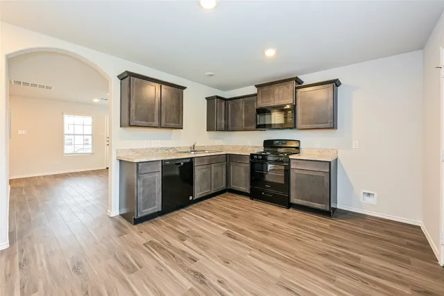 a kitchen with stainless steel appliances granite countertop a stove top oven a sink and dishwasher with wooden floor