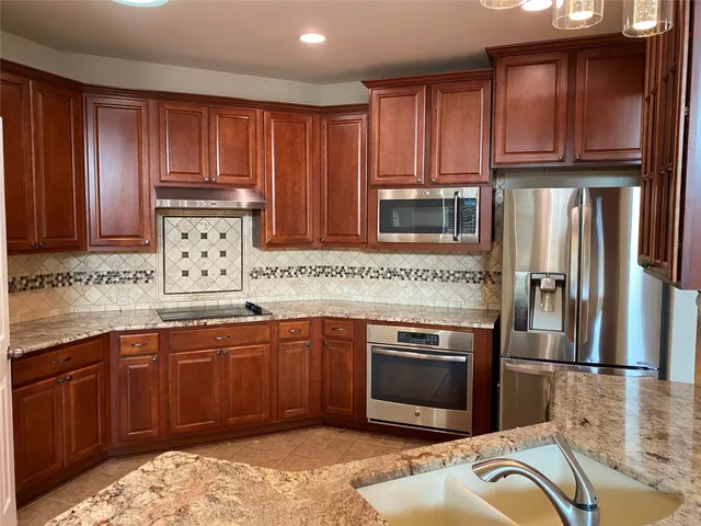 a kitchen with stainless steel appliances granite countertop a stove a sink dishwasher and a refrigerator