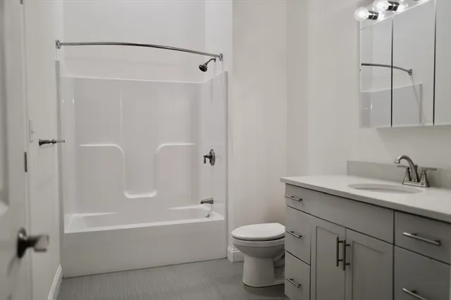 a bathroom with a granite countertop sink a toilet and shower