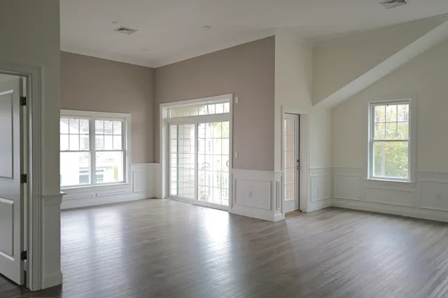 an empty room with wooden floor and windows with curtains view
