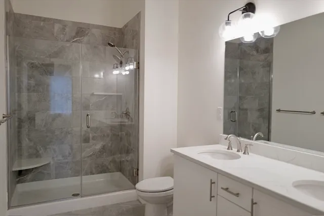 a bathroom with a granite countertop sink a toilet and shower