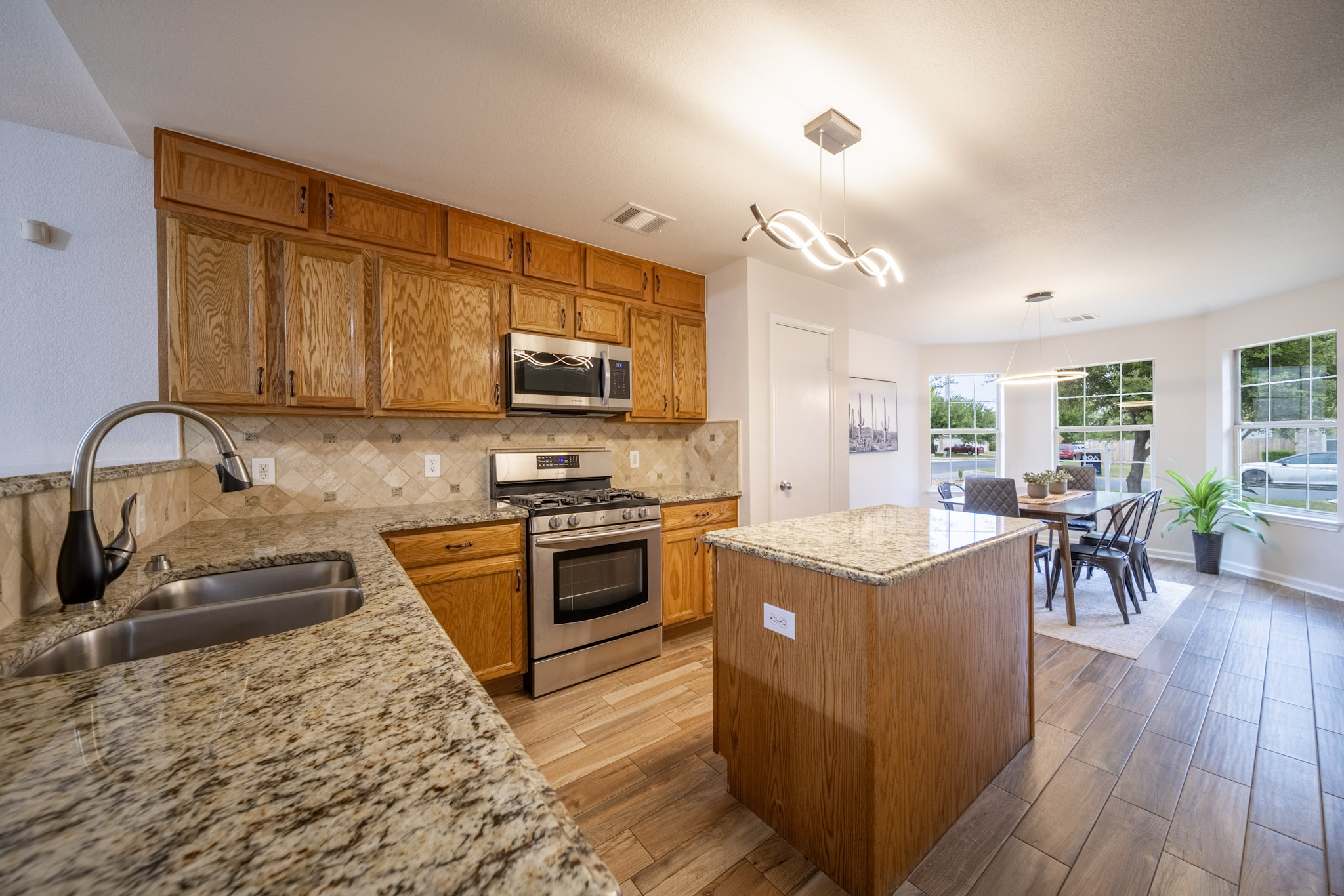 1302 Newbury Street Georgetown, TX 78626 - Photo 8 of 20 a kitchen with stainless steel appliances granite countertop a stove top oven a sink dishwasher a dining table and chairs with wooden floor