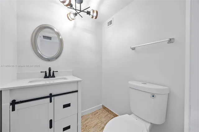 a bathroom with a granite countertop toilet sink and mirror