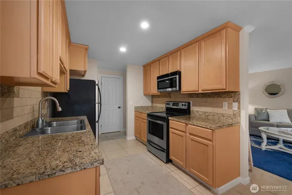 a kitchen with stainless steel appliances granite countertop a sink stove and refrigerator