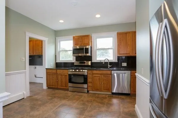 a kitchen with stainless steel appliances granite countertop a refrigerator a sink a stove a washer dryer and a refrigerator