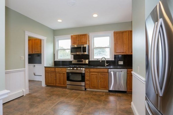 12 White Avenue, Unit 3 Brookline, MA 02467 - Photo 11 of 24 a kitchen with stainless steel appliances granite countertop a refrigerator a sink a stove a washer dryer and a refrigerator