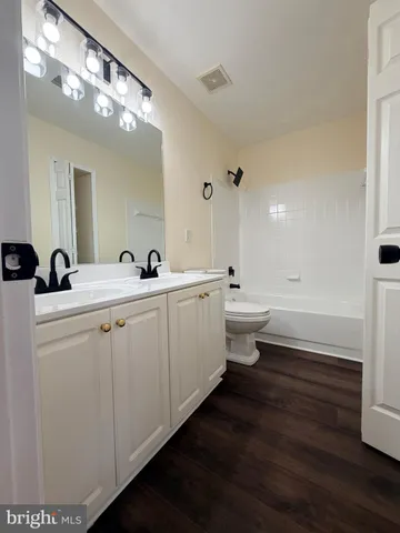 a bathroom with double vanity sinks a toilet a mirror and vanity