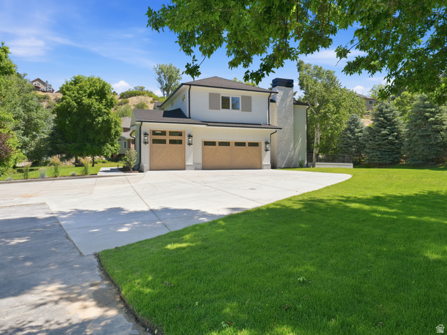 8037 Royal Lane Sandy, UT 84093 - Photo 3 of 72 Contemporary white exterior featuring a dark roofline, wood-finish garage doors, and a paved driveway