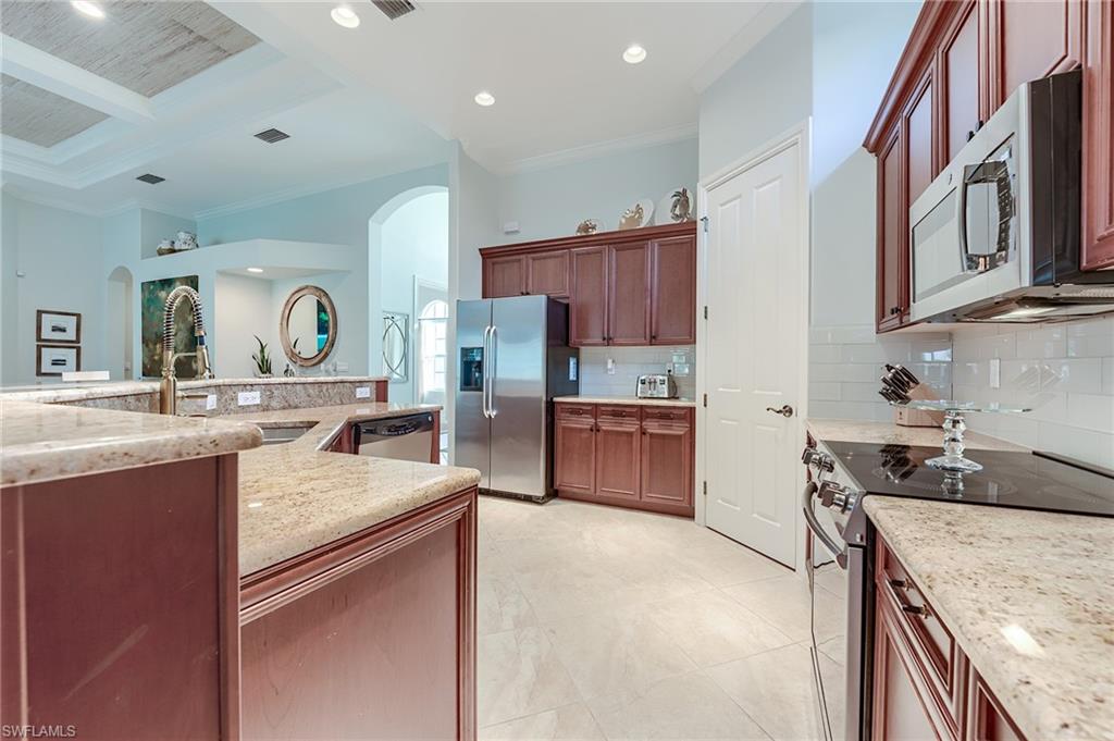 7699 Cottesmore Drive Naples, FL 34113 - Photo 11 of 37 a kitchen with stainless steel appliances granite countertop a sink stove and cabinets