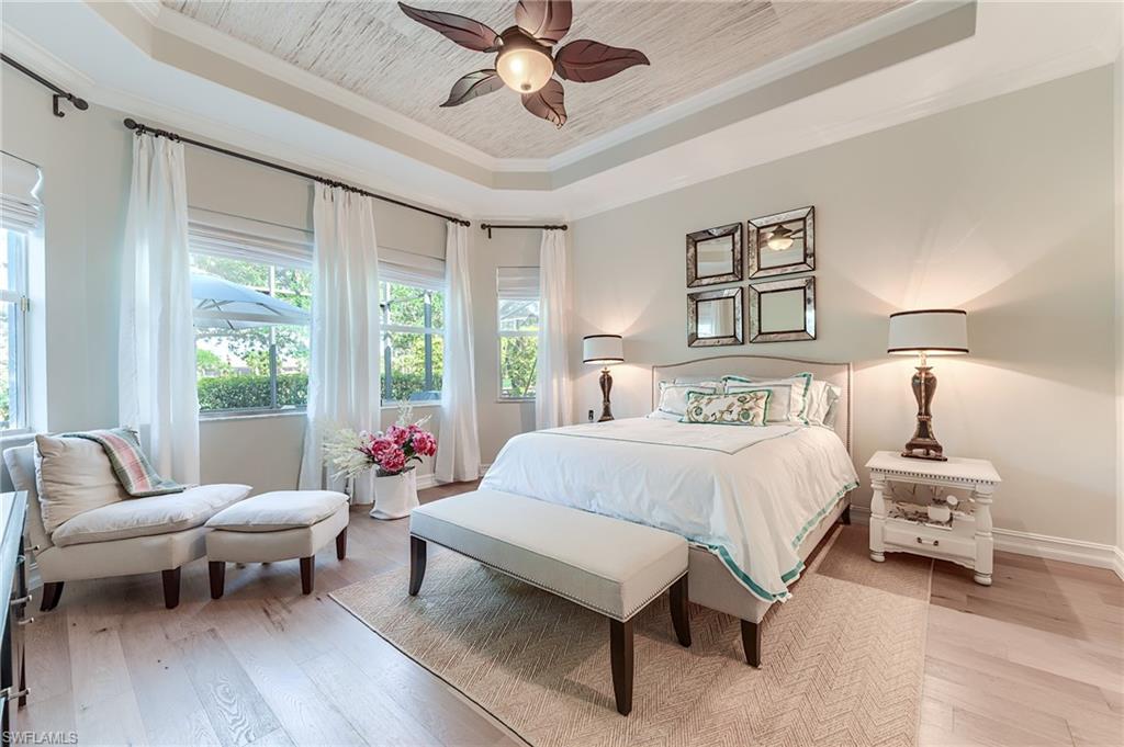 7699 Cottesmore Drive Naples, FL 34113 - Photo 16 of 37 a spacious bedroom with a bed and a chandelier