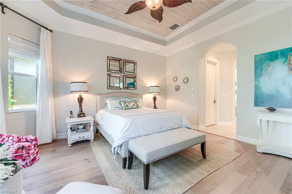 7699 Cottesmore Drive Naples, FL 34113 - Photo 18 of 37 a bedroom with a bed and a chandelier