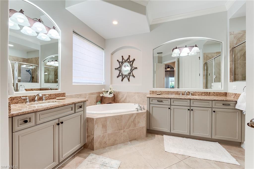 7699 Cottesmore Drive Naples, FL 34113 - Photo 19 of 37 a spacious bathroom with a granite countertop sink a large mirror a bathtub and vanity