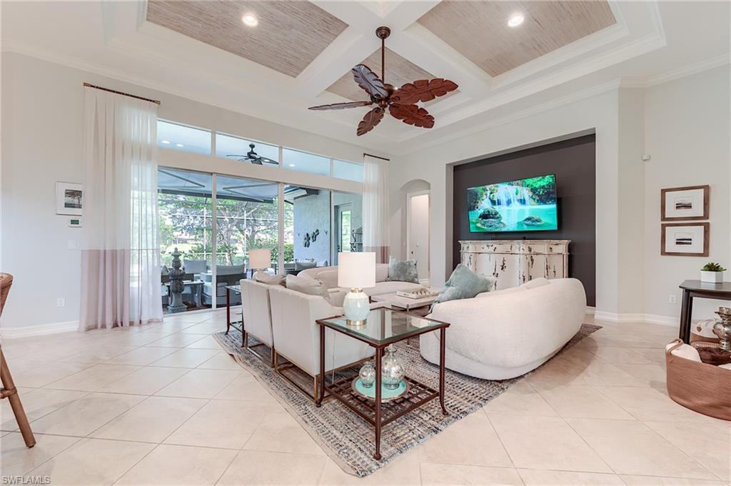 7699 Cottesmore Drive Naples, FL 34113 - Photo 2 of 37 a living room with furniture a chandelier fan and a large window