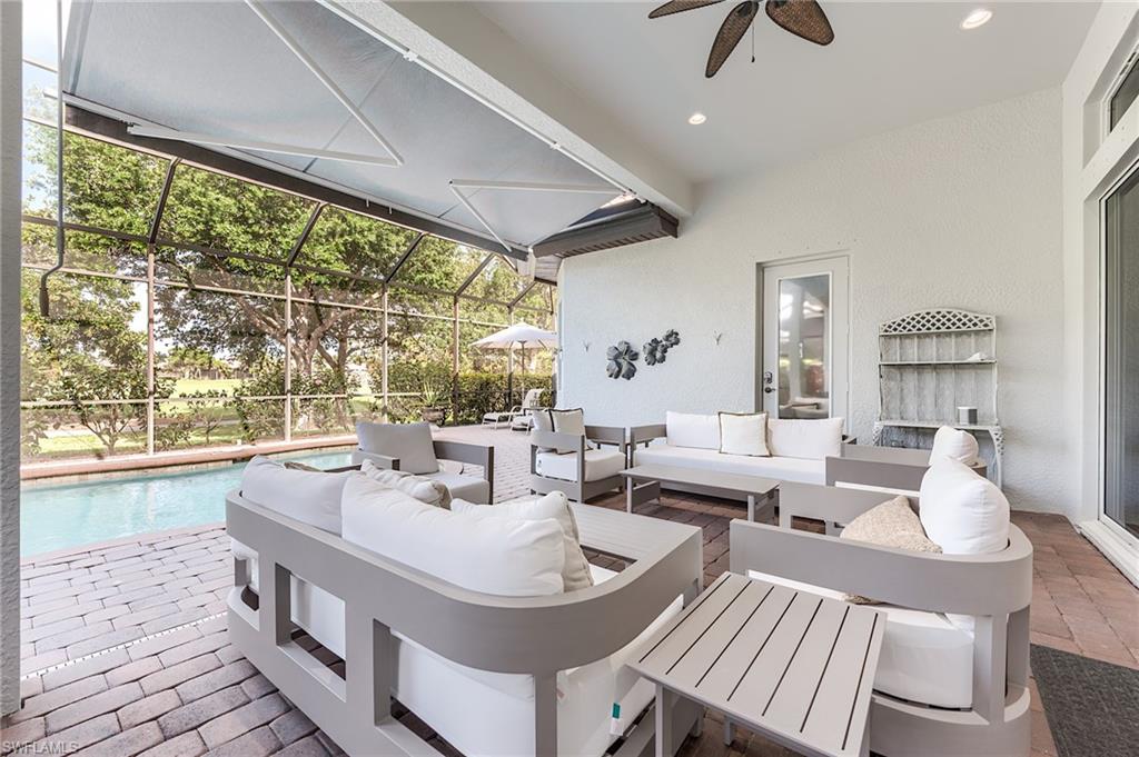 7699 Cottesmore Drive Naples, FL 34113 - Photo 26 of 37 a living room with large windows a table and chairs