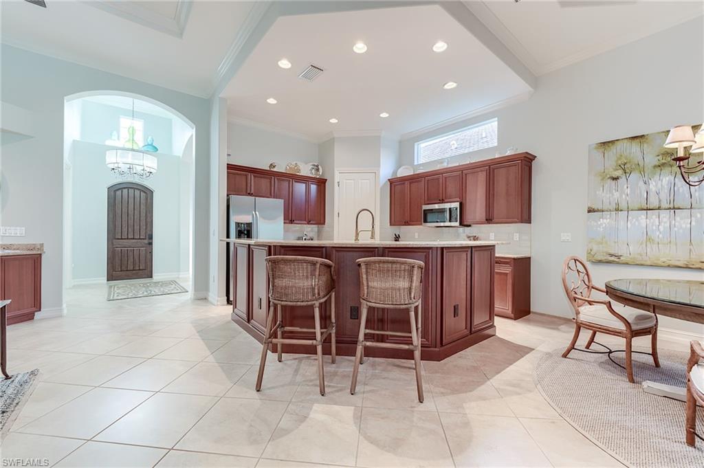 7699 Cottesmore Drive Naples, FL 34113 - Photo 10 of 37 a open kitchen with stainless steel appliances granite countertop a table and chairs in it
