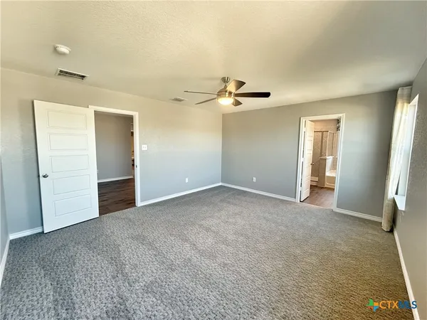 an empty room with a ceiling fan and a window