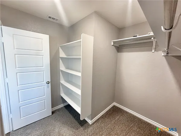a view of an empty room with wooden floor and a bathroom