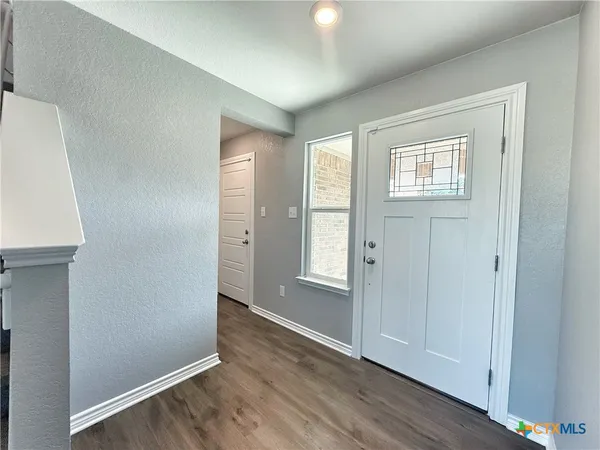 an empty room with wooden floor cabinet and windows