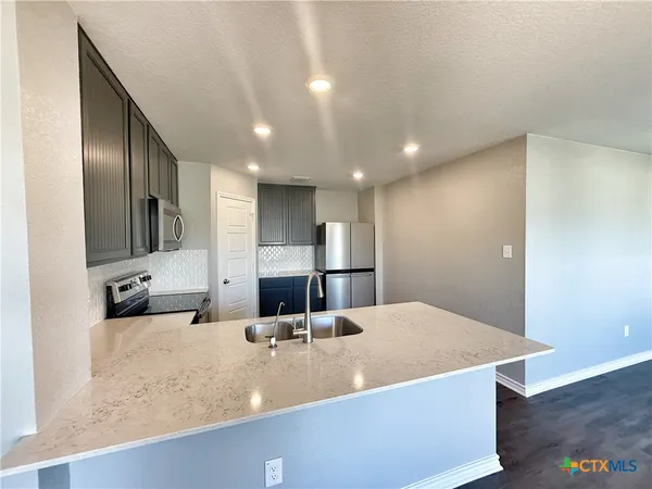 a large kitchen with kitchen island a sink stainless steel appliances and a counter top space