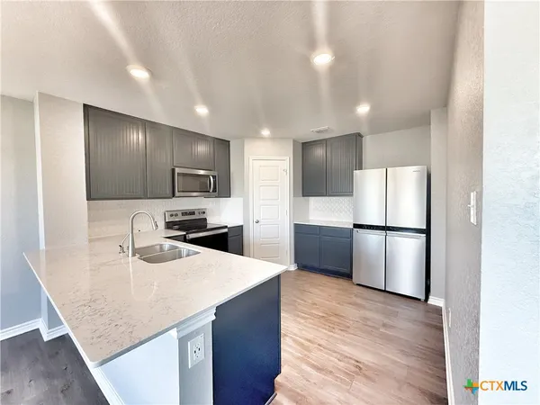 a kitchen with stainless steel appliances granite countertop a sink a refrigerator and a stove top oven
