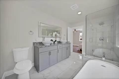a bathroom with a granite countertop sink toilet a large mirror a shower and a bathtub