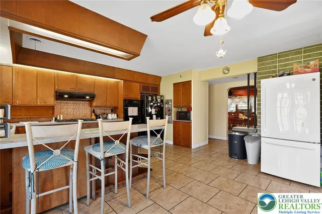a kitchen with a refrigerator a dining table and chairs with wooden floor
