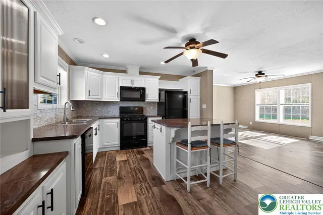 a kitchen with stainless steel appliances kitchen island granite countertop a stove top oven a sink a dining table and chairs with wooden floor