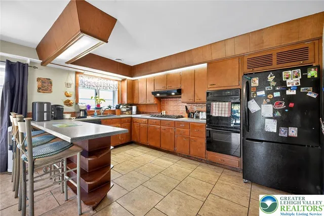 a kitchen with stainless steel appliances kitchen island granite countertop a table chairs and a refrigerator