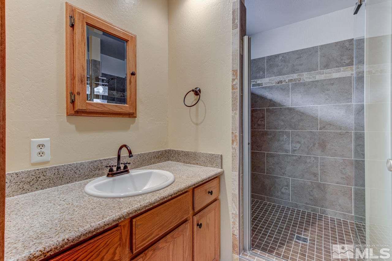 15920 Toll Road Reno, NV 89521 - Photo 18 of 24 a bathroom with a granite countertop sink a mirror and shower