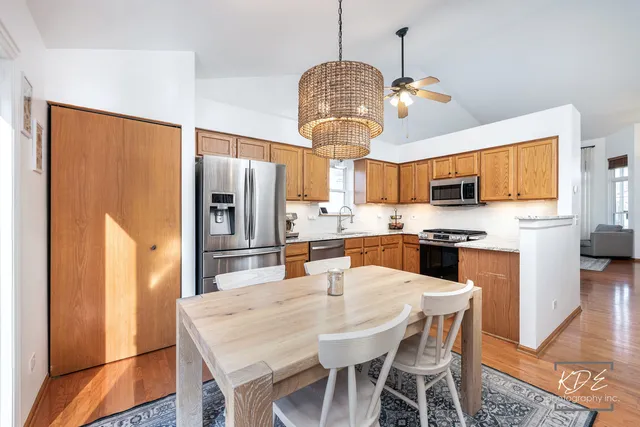 a kitchen with stainless steel appliances a dining table chairs and refrigerator