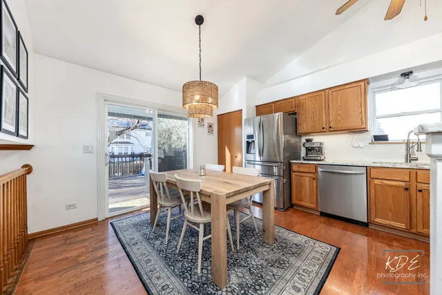 a kitchen with stainless steel appliances granite countertop a stove a sink dishwasher a refrigerator with a dining table and chairs with wooden floor