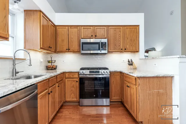 a kitchen with stainless steel appliances a stove a sink cabinets and a window